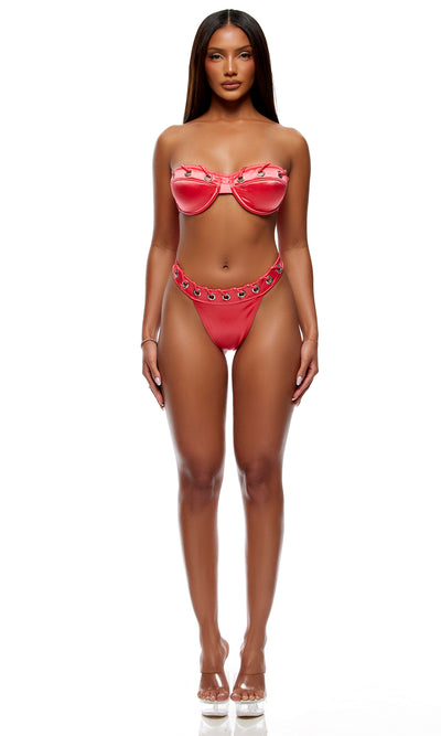 A woman modeling a two-piece bikini set consisting of a strapless bandeau-style top with a bow detail and matching high-cut bottoms with a star pattern, in a vibrant pink color, shot against a solid white background.