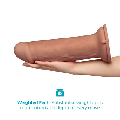 A realistic flesh-toned dildo shown resting on a person's hand against a white background, with blue text below reading 'Weighted Feel - Substantial weight adds momentum and depth to every move' and a small scale icon.