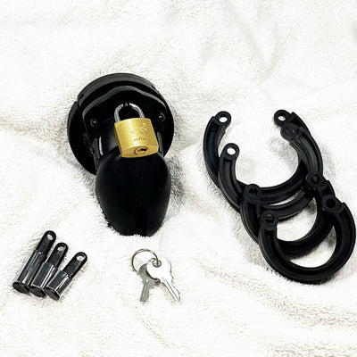 Black chastity device with gold lock, key, and additional parts on a white background