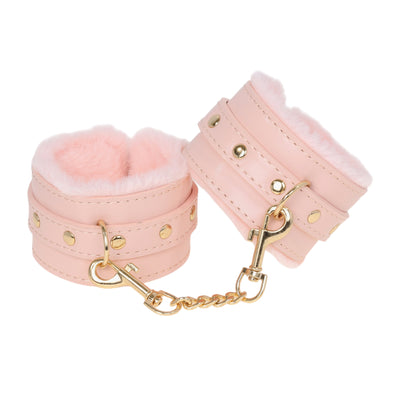 Pink leather cuffs with gold chain on a white background
