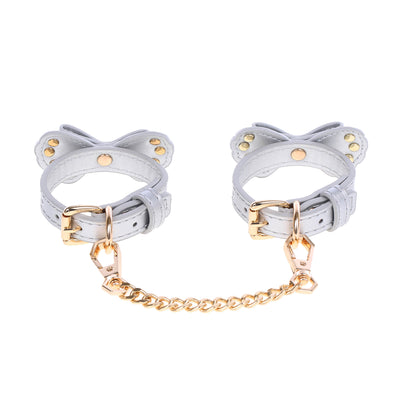Pair of silver bow-shaped cuffs with gold accents on a white background