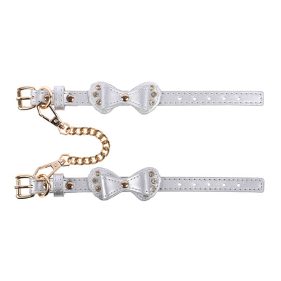 Pair of silver bow-shaped cuffs with gold accents on a white background