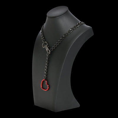 Black chain necklace with a red heart pendant on a black mannequin bust.