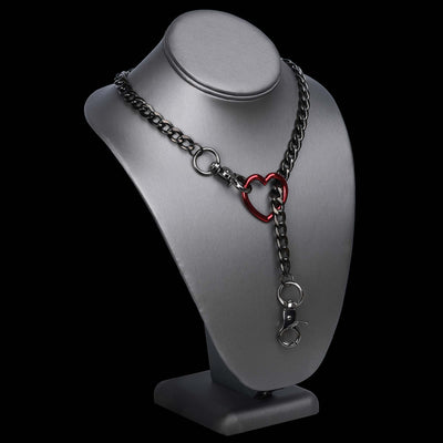 A dark gunmetal chain necklace with a red heart-shaped ring clasp, displayed on a matte gray jewelry bust against a solid black background.