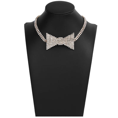 A rhinestone-encrusted choker necklace with a bow-tie center and matching chain, displayed on a black jewelry bust against a white background.