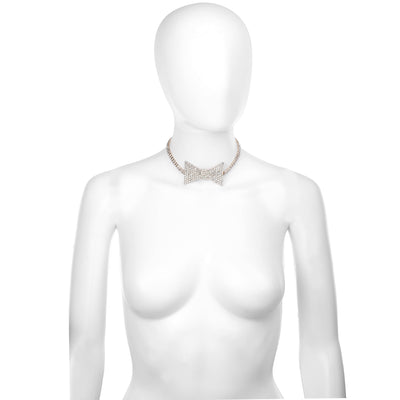 A gold-toned choker necklace with a large bow-shaped center, displayed on a white mannequin torso against a plain white background.