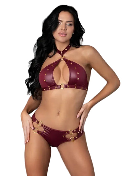 A woman modeling a two-piece strappy bikini in deep burgundy faux leather with gold-tone studs and buckles, set against a plain white background.